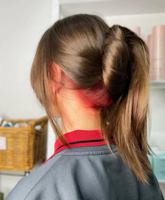 Brown hair with a vivid red section underneath, styled up